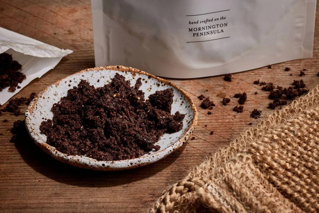 close up of a bowl with coffee scrub on it next to a pouch of coffee scrub