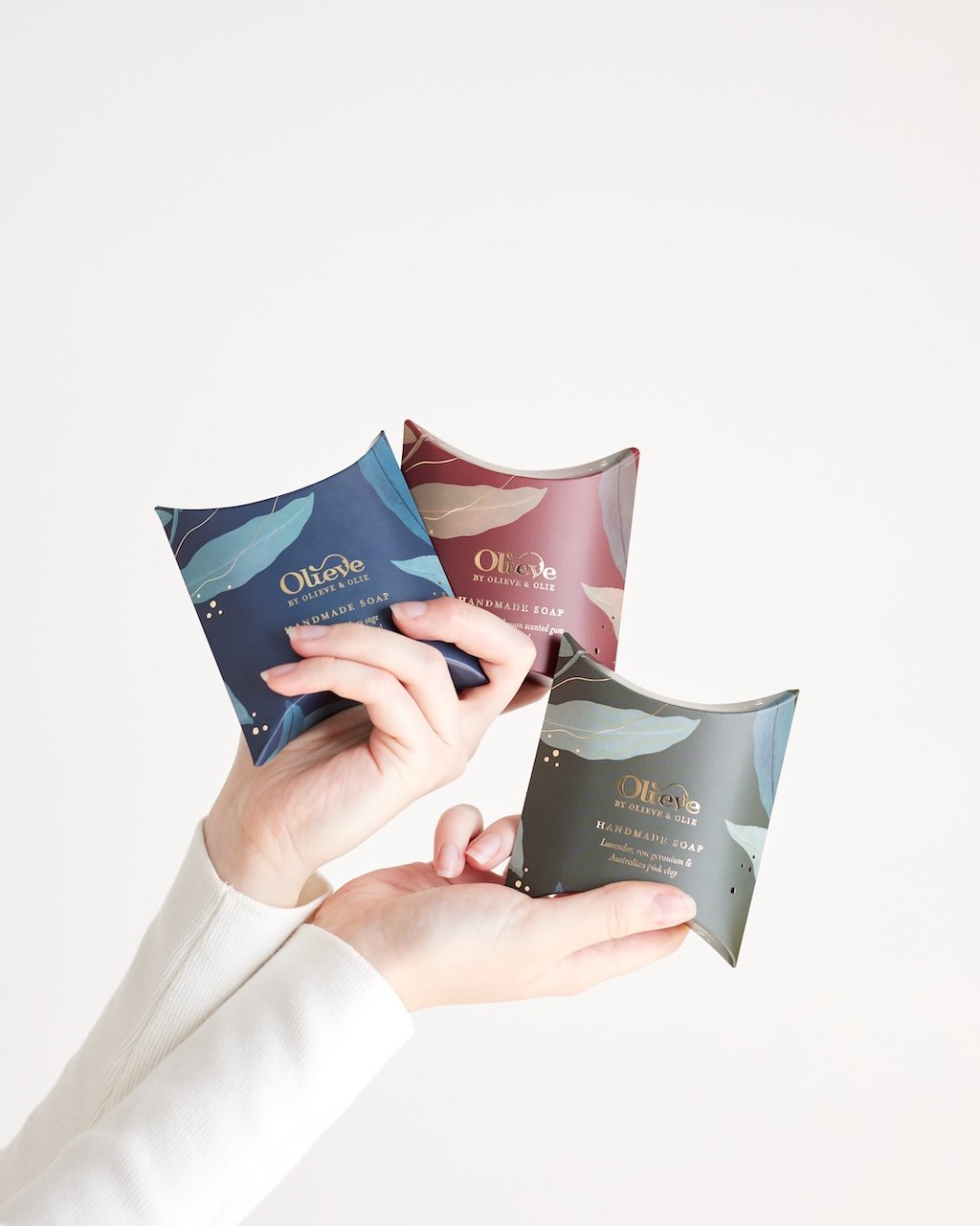 a hand holding 3 gift soap boxes