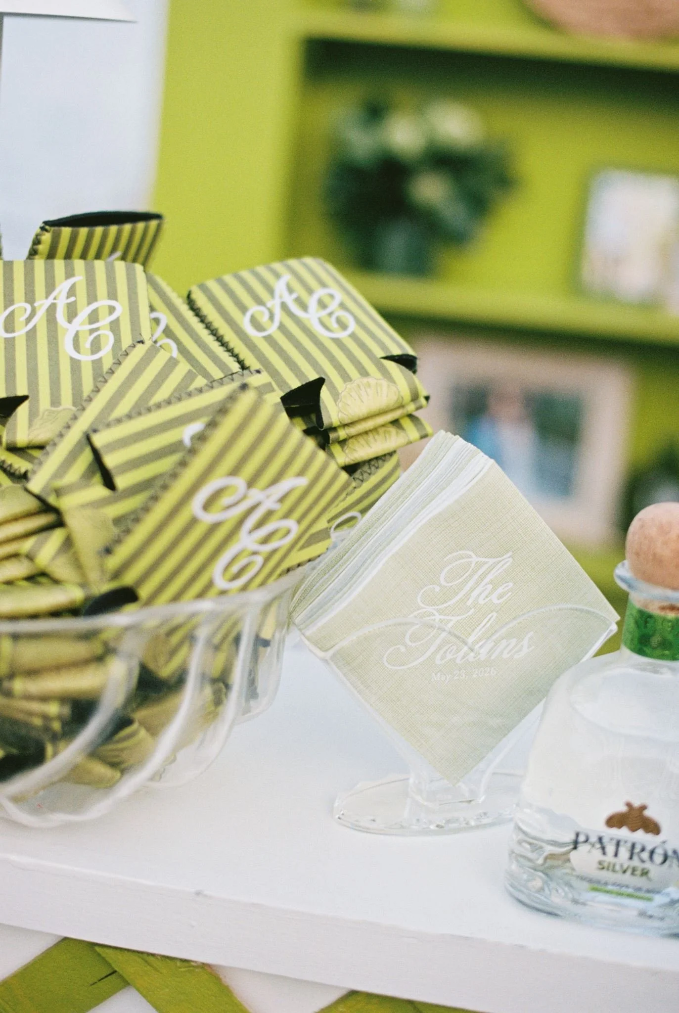 Close-up of small favor boxes with yellow and black striped design and white cursive lettering, displayed in a clear glass container at a party or celebration.