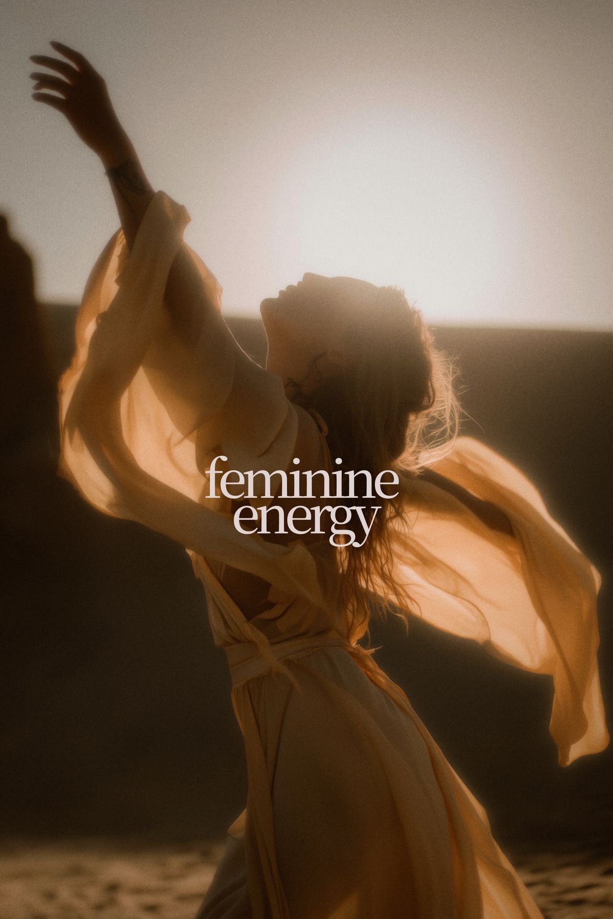 A woman in a flowing, light-colored dress, with long, curly hair, is basking in sunlight on a beach, with the words "feminine energy" overlaid on the image.