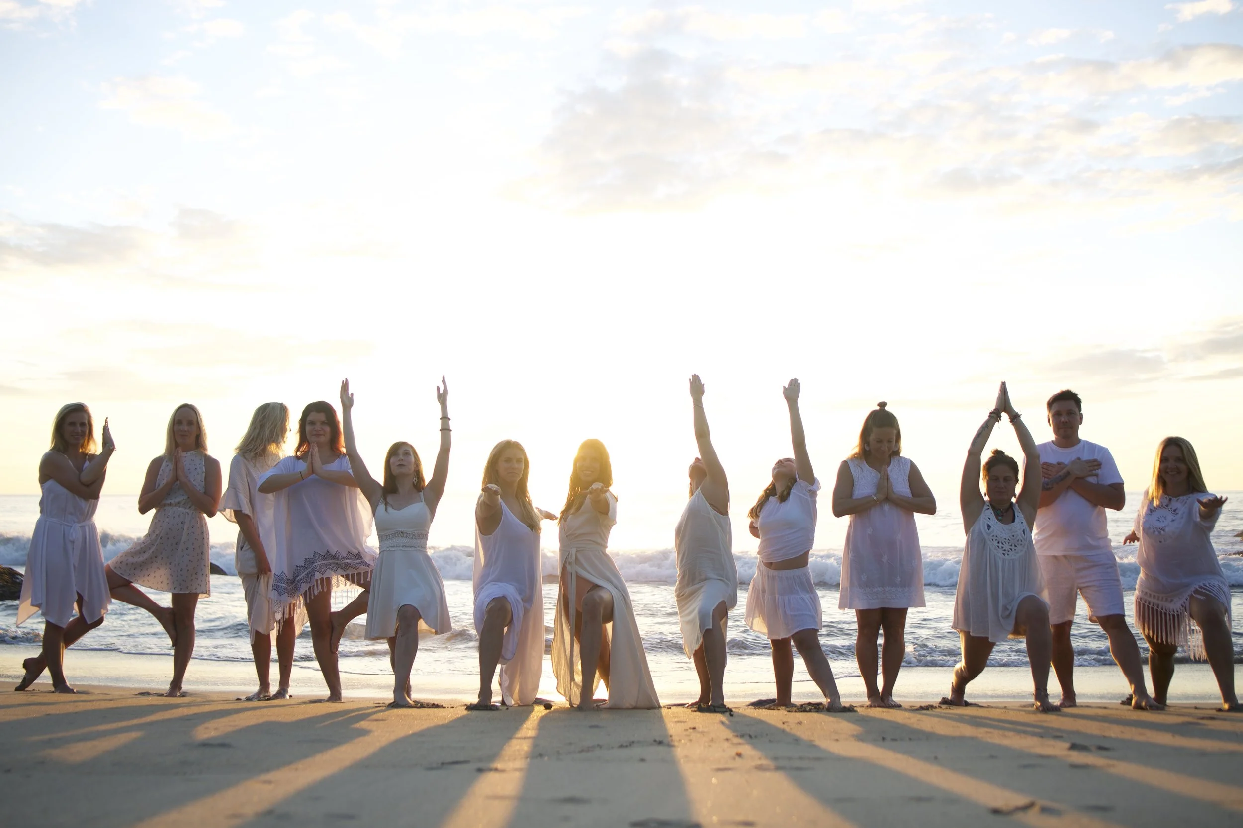 Group yoga practice on the beach at sunset during an Eva Estlander retreat
