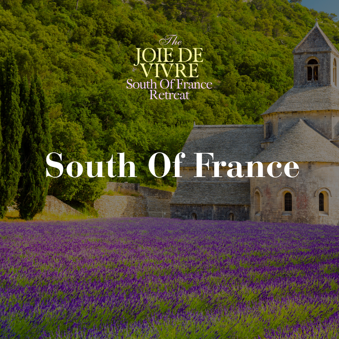 A scenic view of a historic stone church surrounded by lush green trees, with a field of blooming purple lavender flowers in the foreground. Overlaid text reads 'The Joie De Vivre South Of France Retreat' and 'South Of France'.