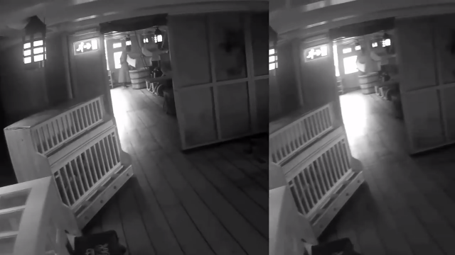 A still image from the video that shows what appears to be a woman wearing a dress in the far background in the frame to the left, who then seems to walk through a wall and disappear.