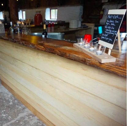 Light wood bar with live edge wood bar op with candles and chalkboard sign on it