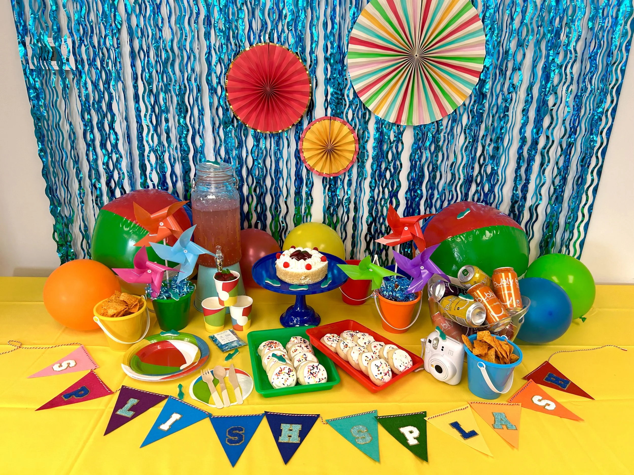 Food set up on table with beach balls and a banner that says "Splish Splash"