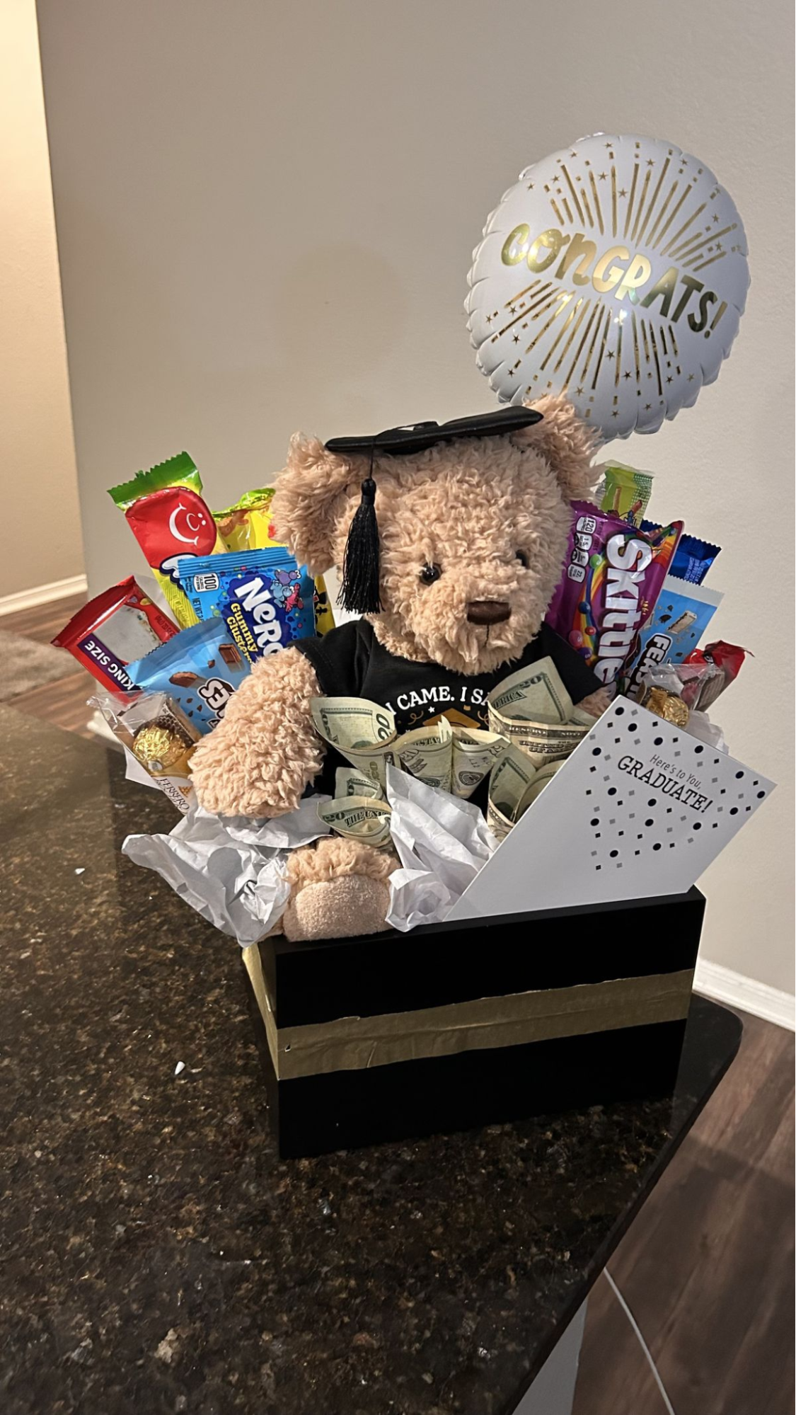 Gift basket with a teddy bear surrounded by candy and cash