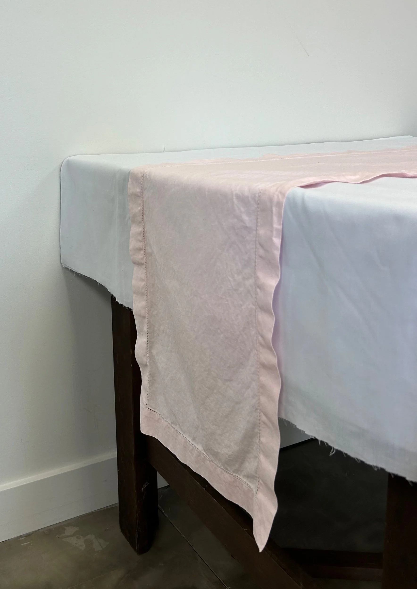 Light pink linen table runner on white table cloth to add frill to your table setting