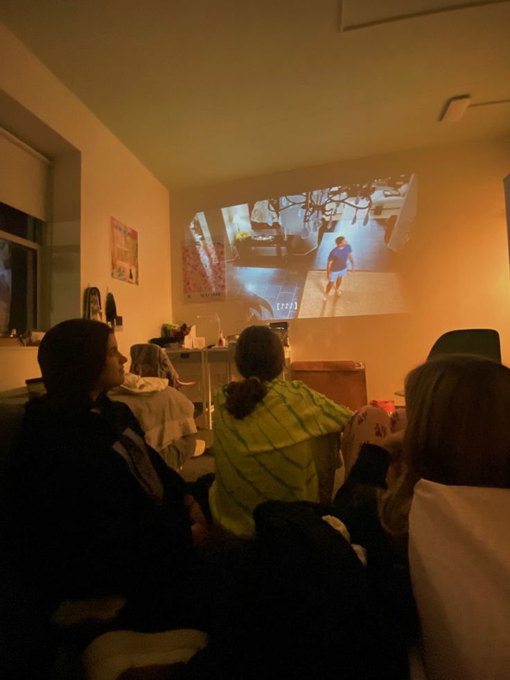 Group of friends watching movie being projected onto wall