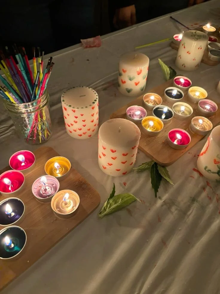 Column candles being painted with wax from colourful tea lights