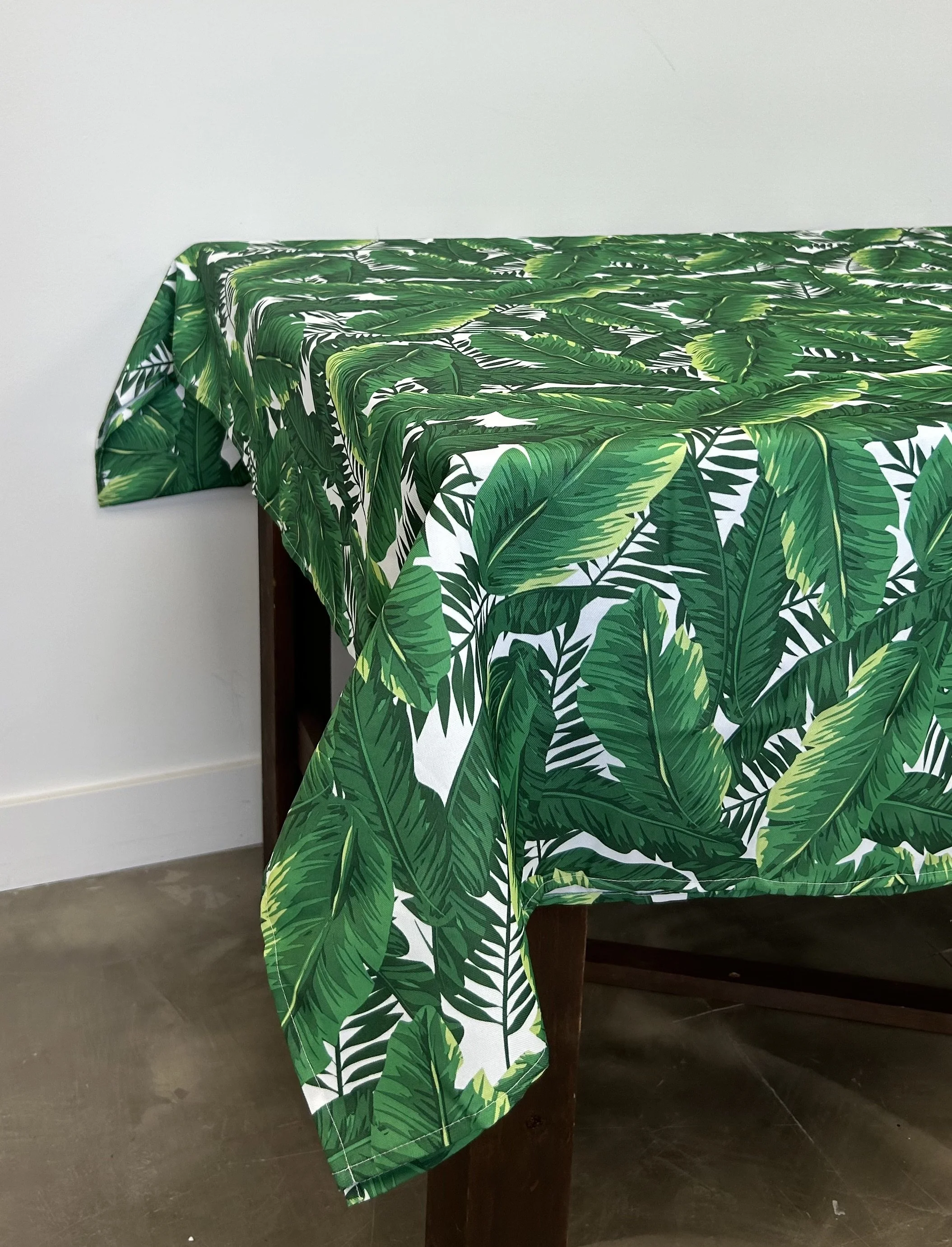 Get on island time with this tropical leaf table cloth with green leaves and a white background