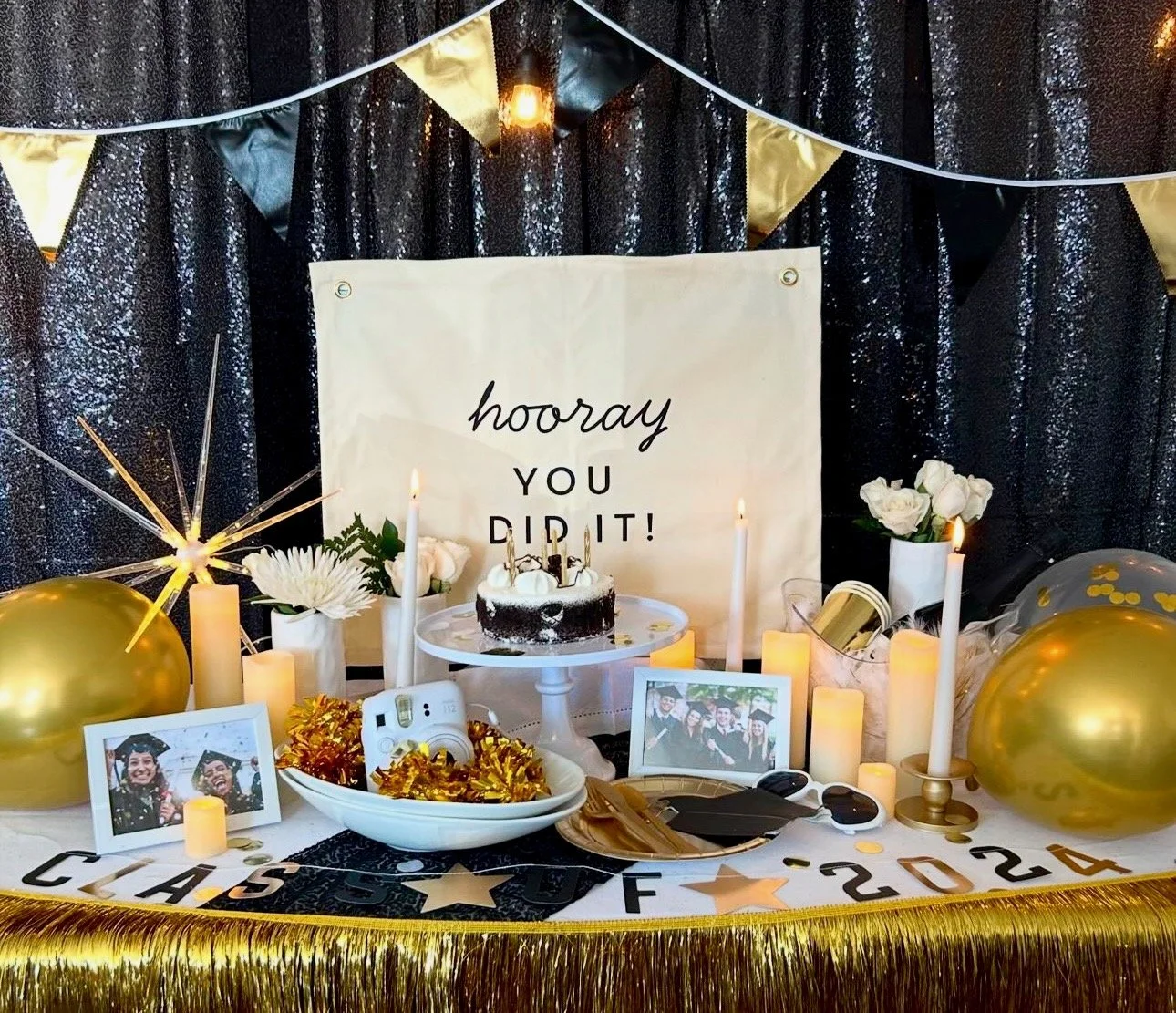 Cake on table with gold accents and balloons with a sign that says "Hooray you did it!" against a black sequin backdrop