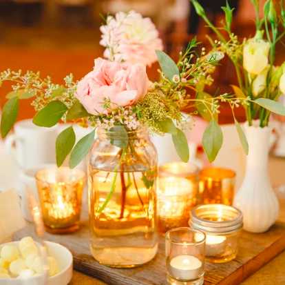 Wood disc on centre of table with flowers in vases and tea candles