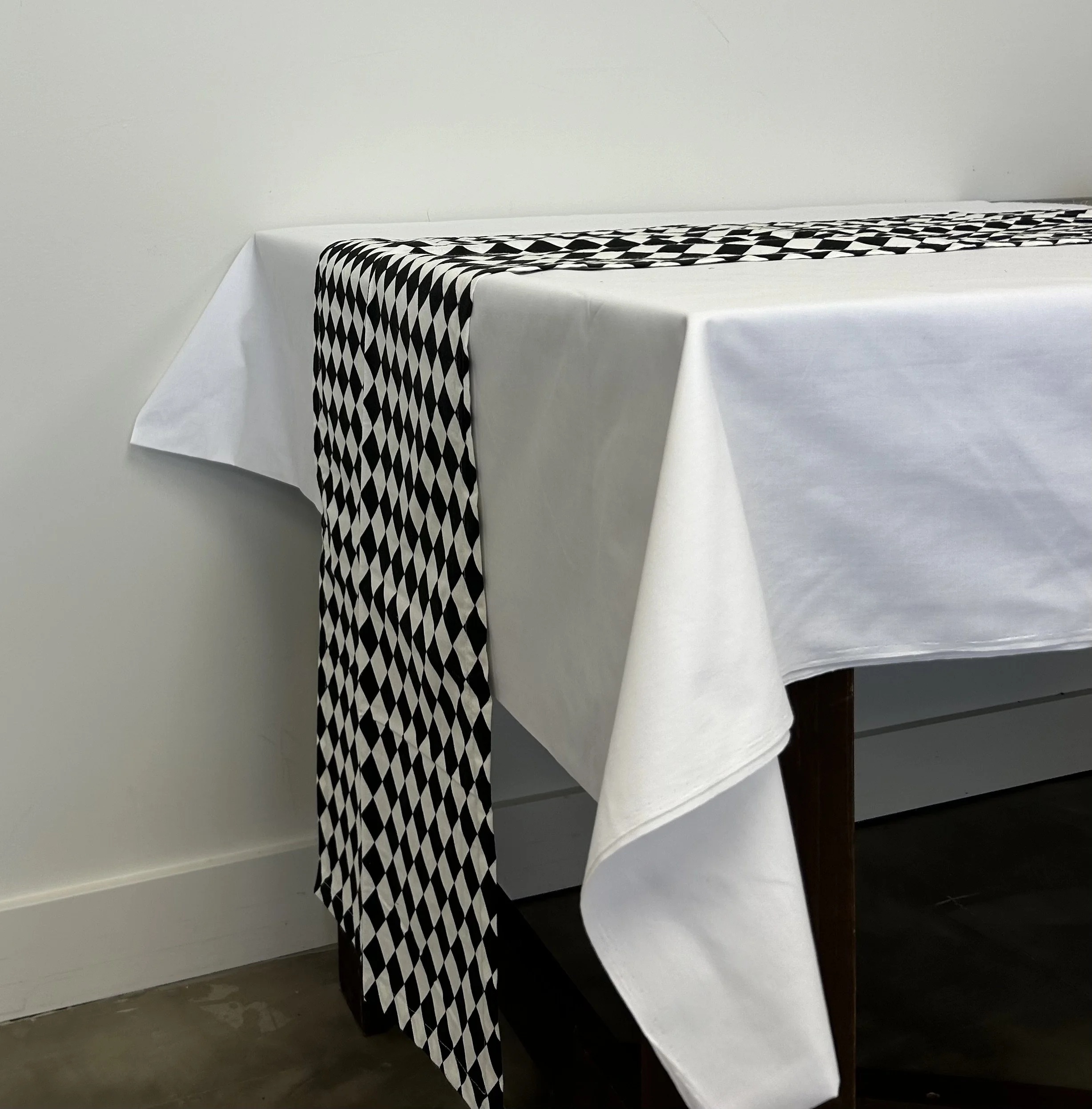 Black and white harlequin table runner on white table cloth to bring the attention to your table scape