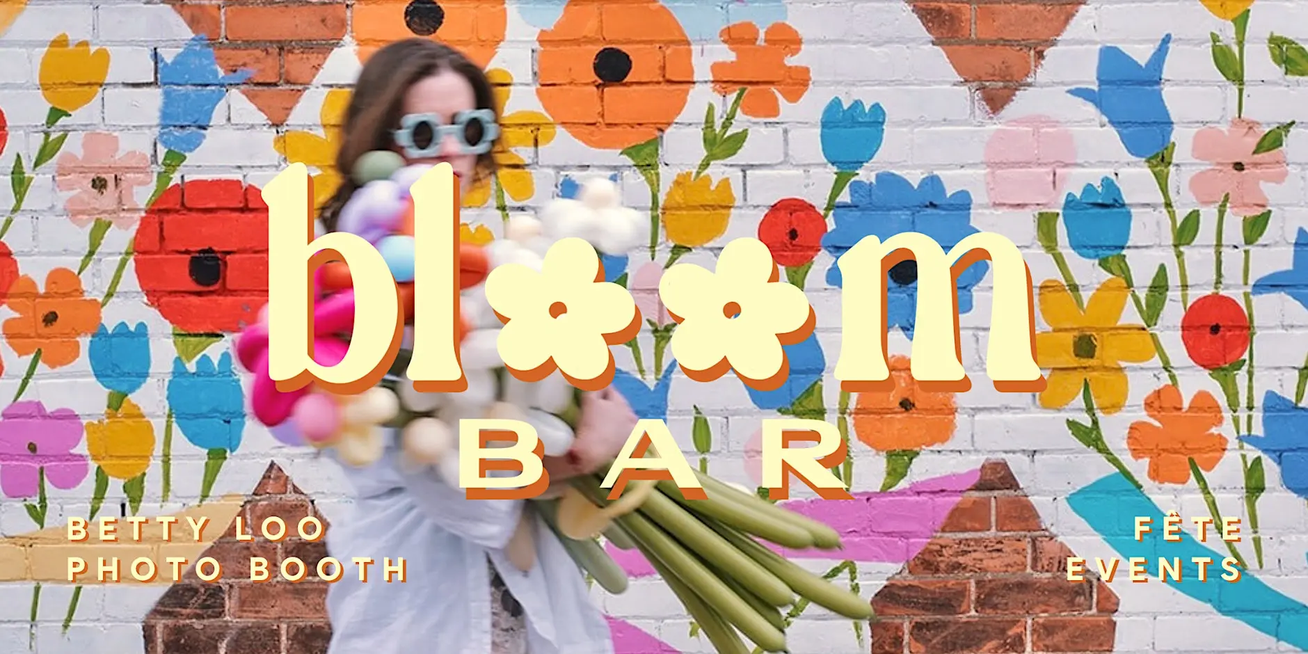Woman carrying flower balloons in front of floral mural with bloom bar logo overlay