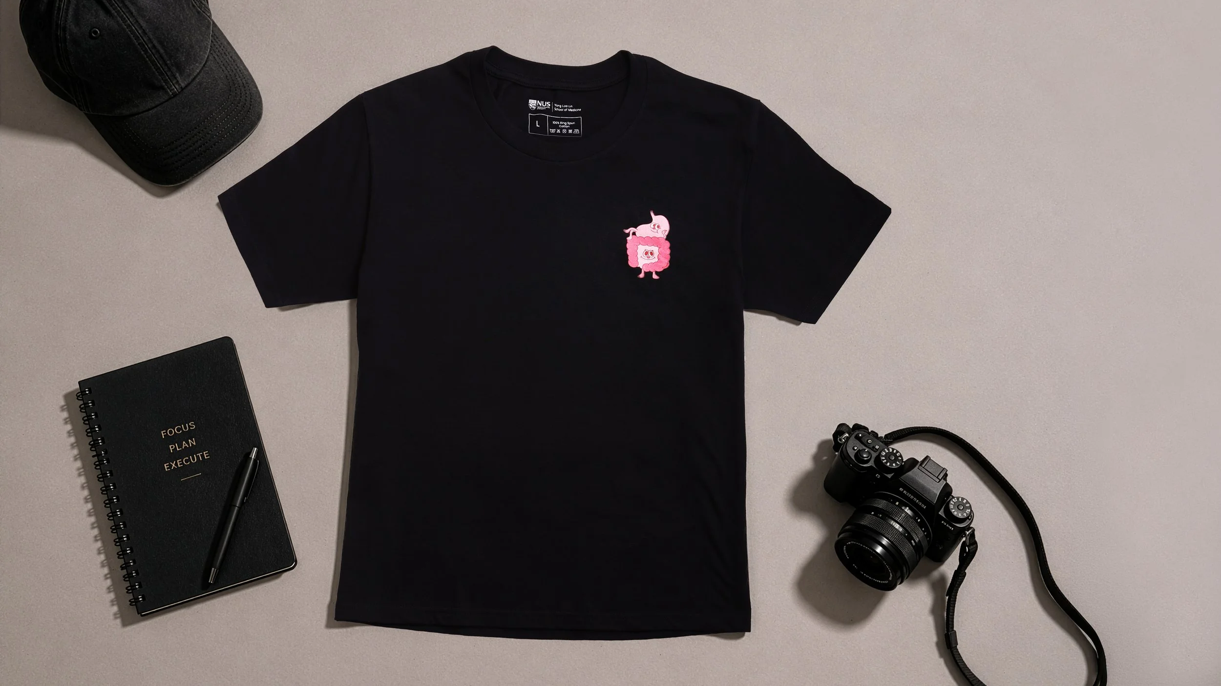 Custom black cotton round neck t-shirt with pink embroidered character design for National University of Singapore. Student appreciation gifts