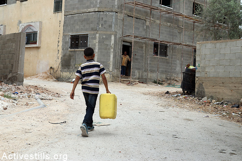 Palestinian child carries water gallon in Qarawat Bani Hassan village, West Bank, May 23, 2015. (photo: Ahmad al-Bazz / Activestills.org)