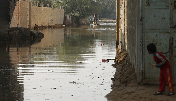 A boy looks at Palestinians as they ride a horse cart on a street flooded with sewage water from a sewage treatment facility in Gaza City, Gaza, Nov. 14, 2013. (photo by REUTERS/Mohammed Salem)