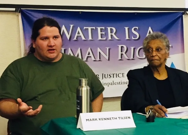 Dorotea Manuela of Boston's Color of Water Project listens as Mark Kenneth Tilsen describes the Lakota struggle to protect water resources.