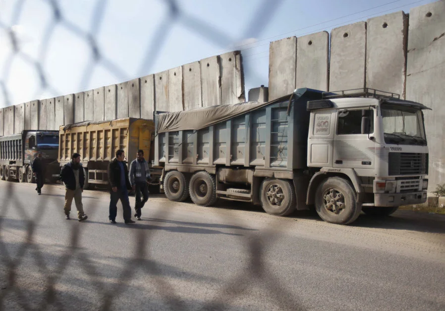 Palestinians walk past trucks loaded with gravel at the Kerem Shalom crossing between Israel and the southern Gaza Strip December 30, 2012.. (photo credit: REUTERS)