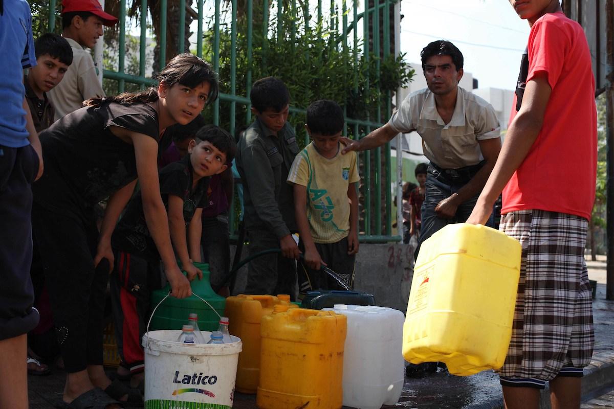 Palestinian children fill plastic bottles and water containers with drinking water from a public tap in Jabilia in the northern Gaza Strip. Ashraf Amra/Aplmages