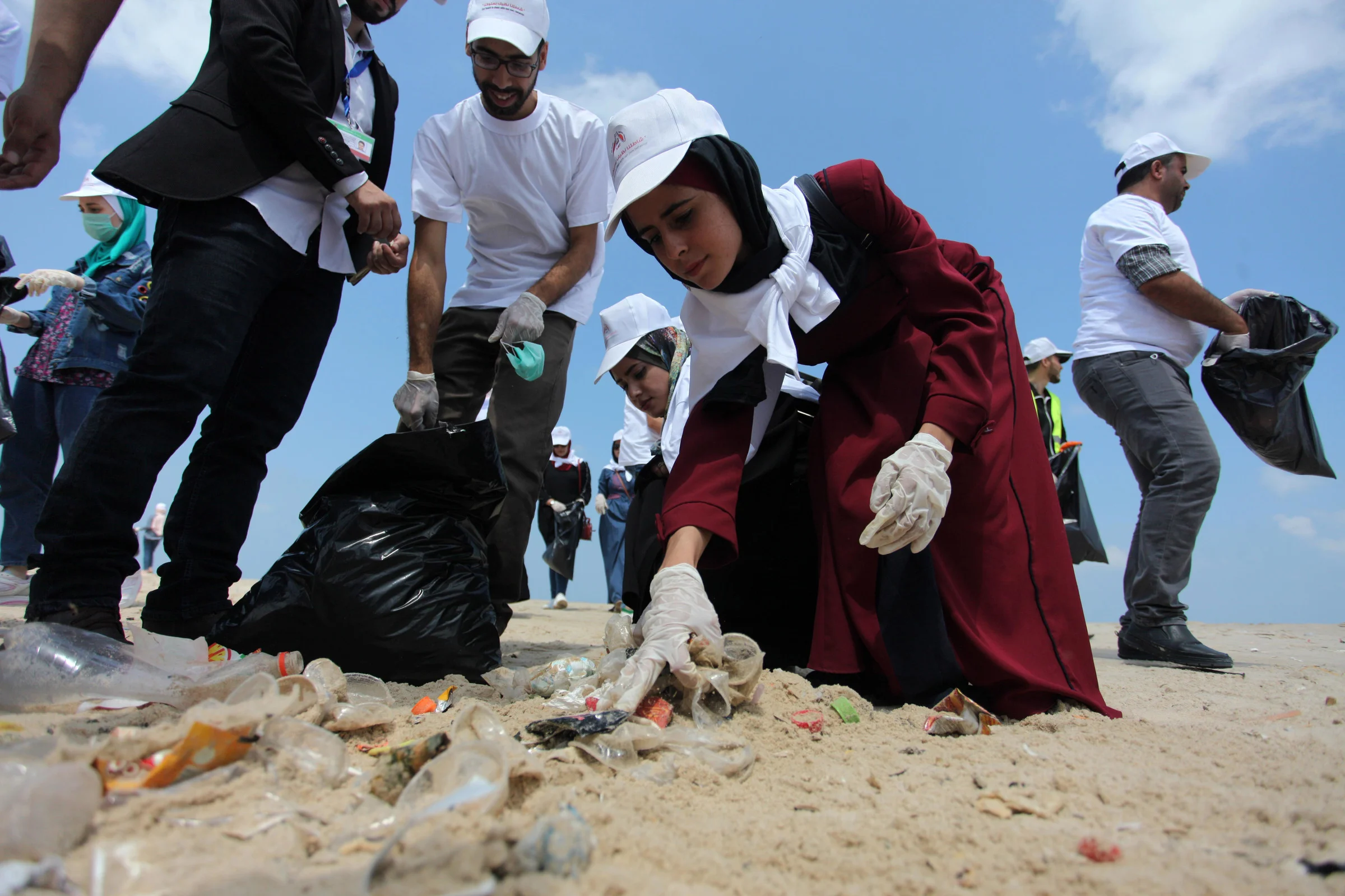 Palestinian youth clean up a Gaza City beach on August 7. Mahmoud Ajjour/APA images