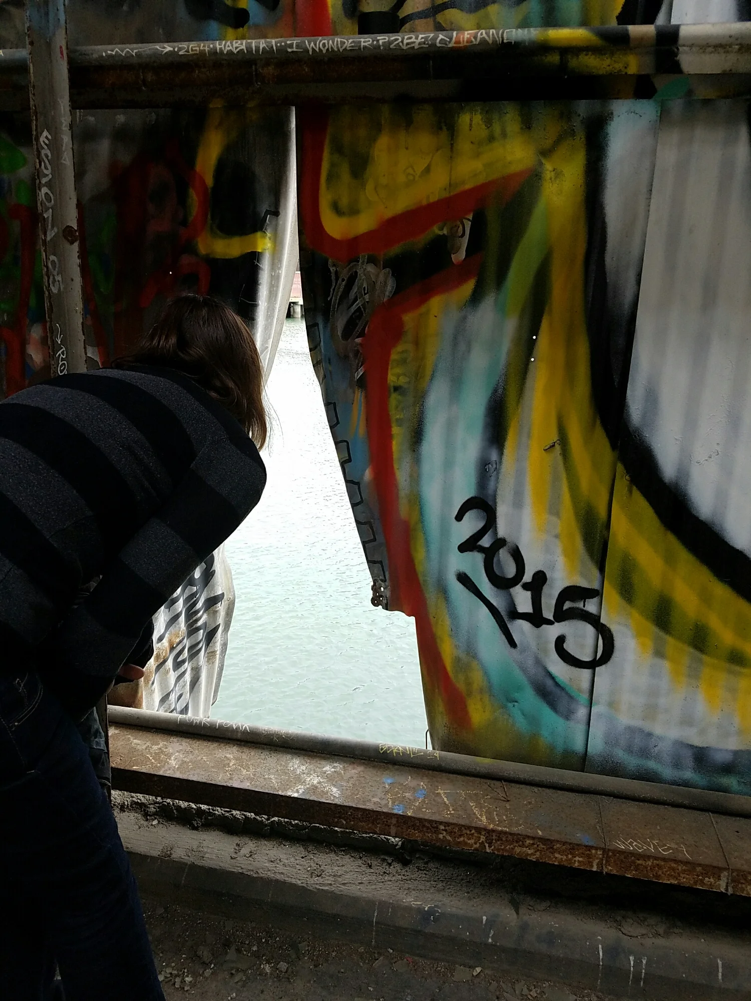 Lexie looks out the torn warehouse wall. 