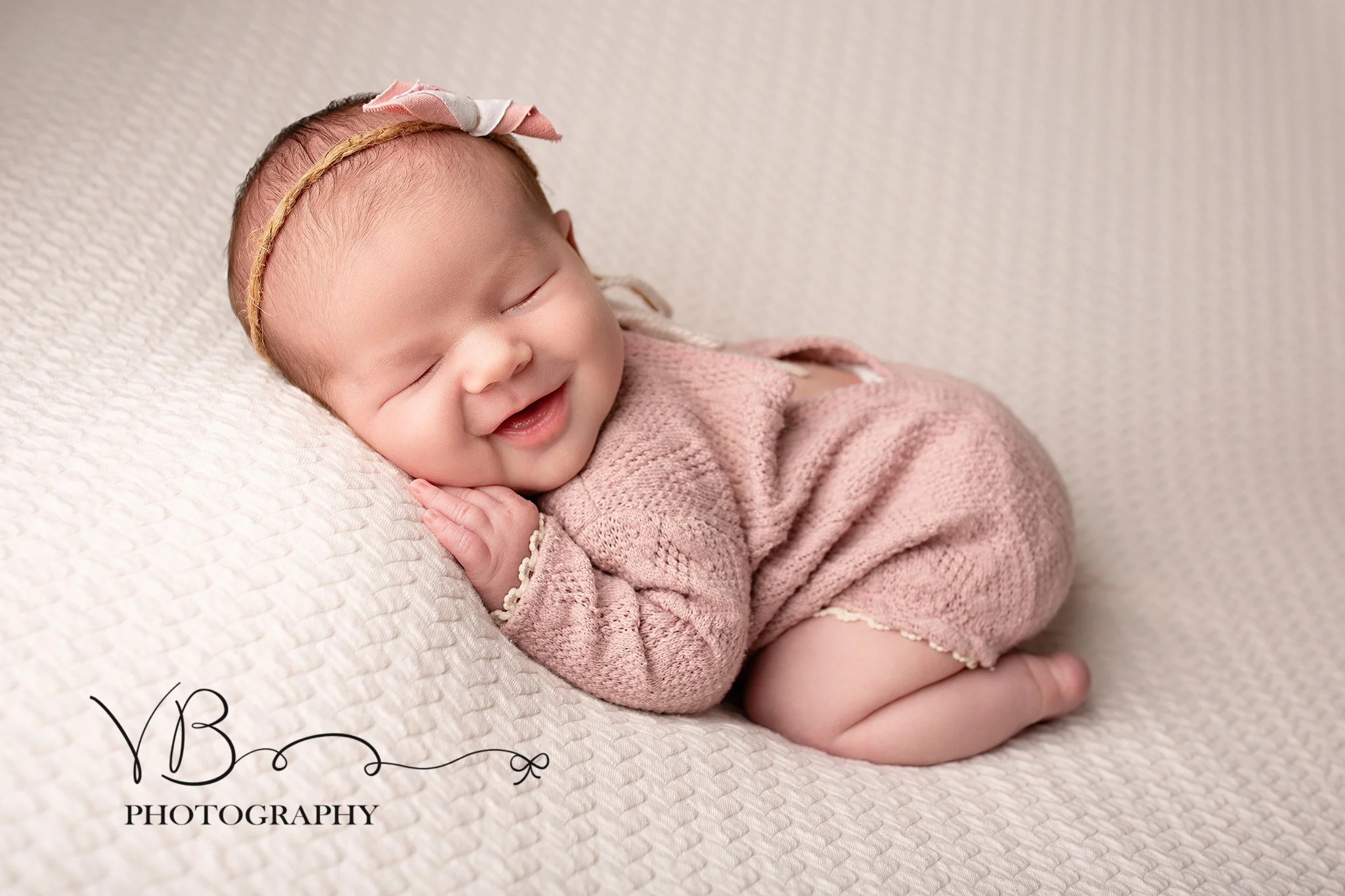 baby girl smiling during newborn posed photoshoot colchester