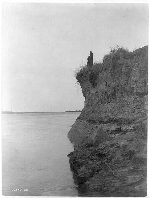 Photograph by Edward S. Curtis, c. 1908. "Mandan man wrapped in buffalo robe standing on cliff overlooking the Missouri River." From Wikimedia Commons .
