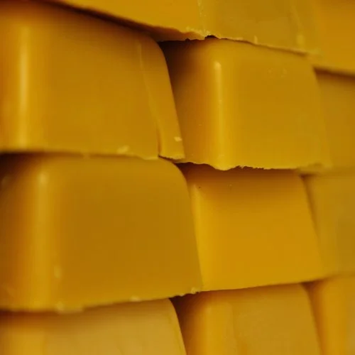 Close-up of stacked yellow beeswax blocks.
