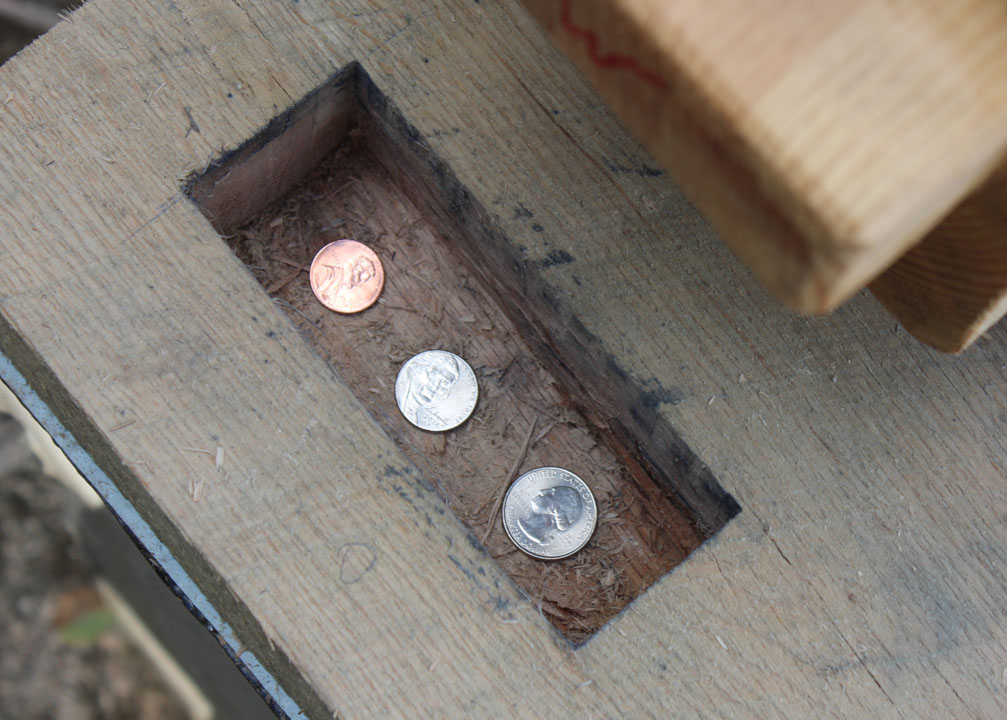 Coins placed in a mortise on raising day.