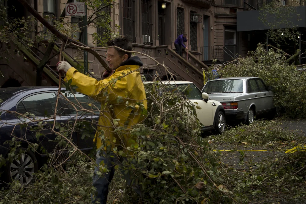 Residents remove downed trees in Manhattan.