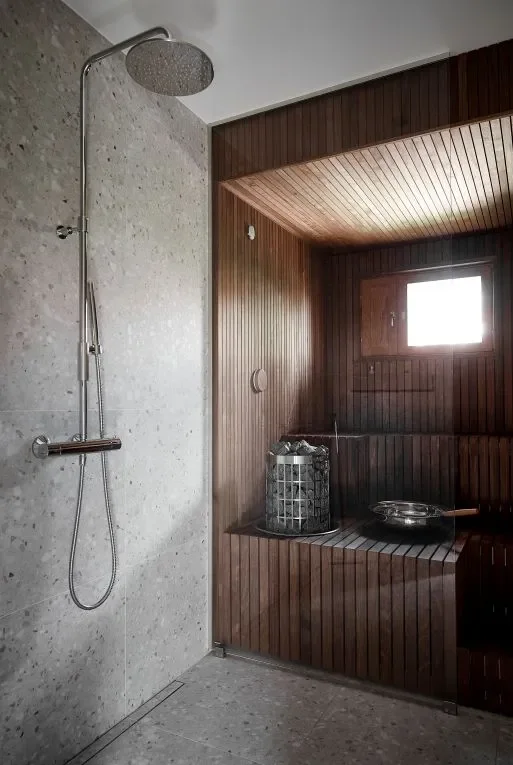 Pieni sauna lasiseinällä ja tummalla paneelilla.