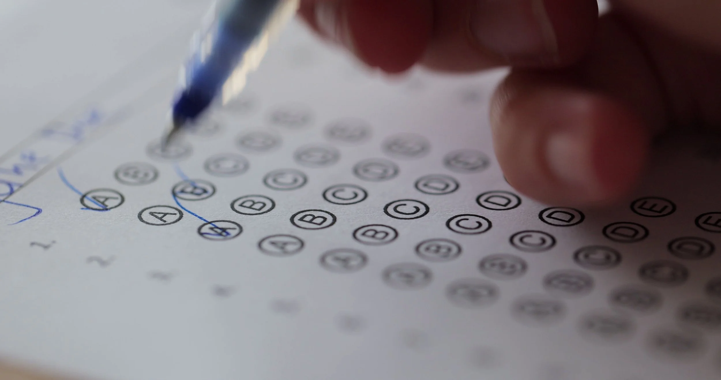 close-up-view-of-hands-of-university-student-woman-taking-exam-filling-out-paper-sheet-SBI-350493211.jpg