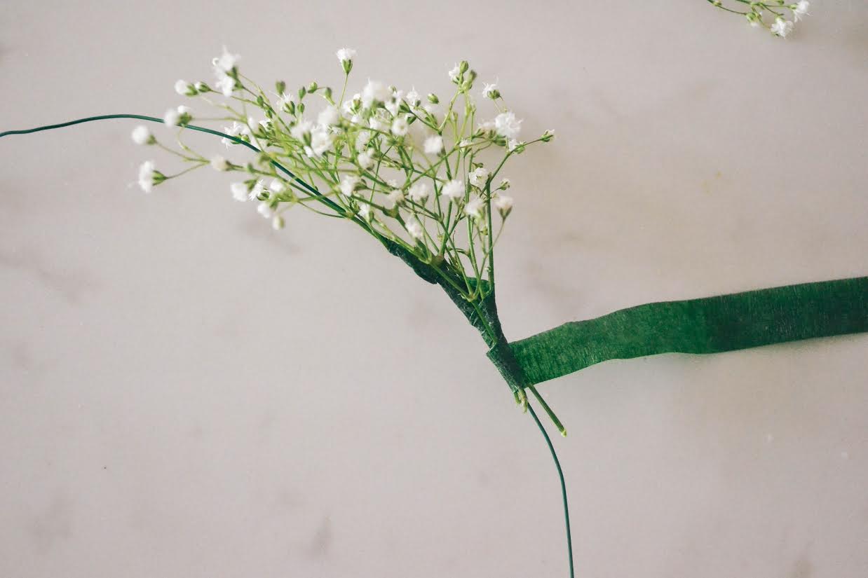 Keep placing sprigs of flowers on top of the last, slowly making your way down the wire while wrapping the tape as you go.
