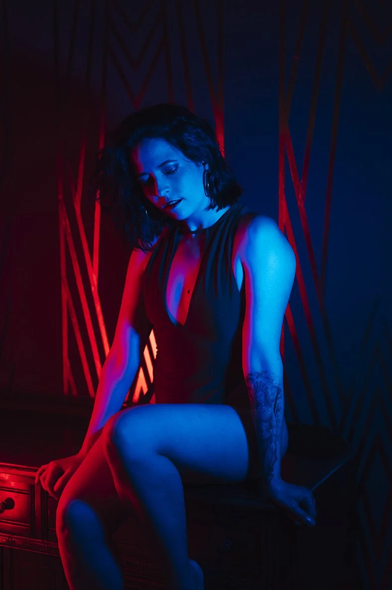 woman posing for mini boudoir photoshoot in Toronto at Scandaleuse Photography in a red and blue neon lights set