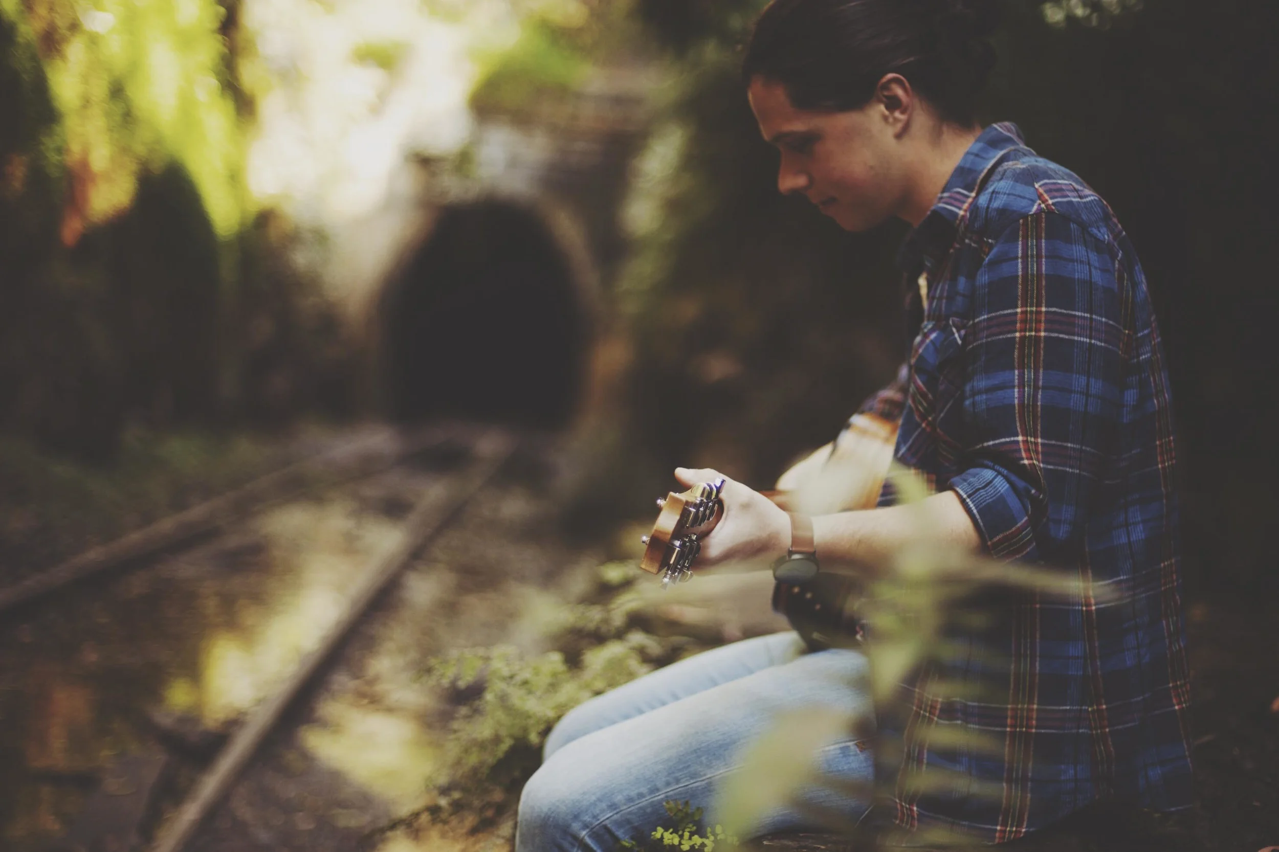 man standing in rainforest with guitar