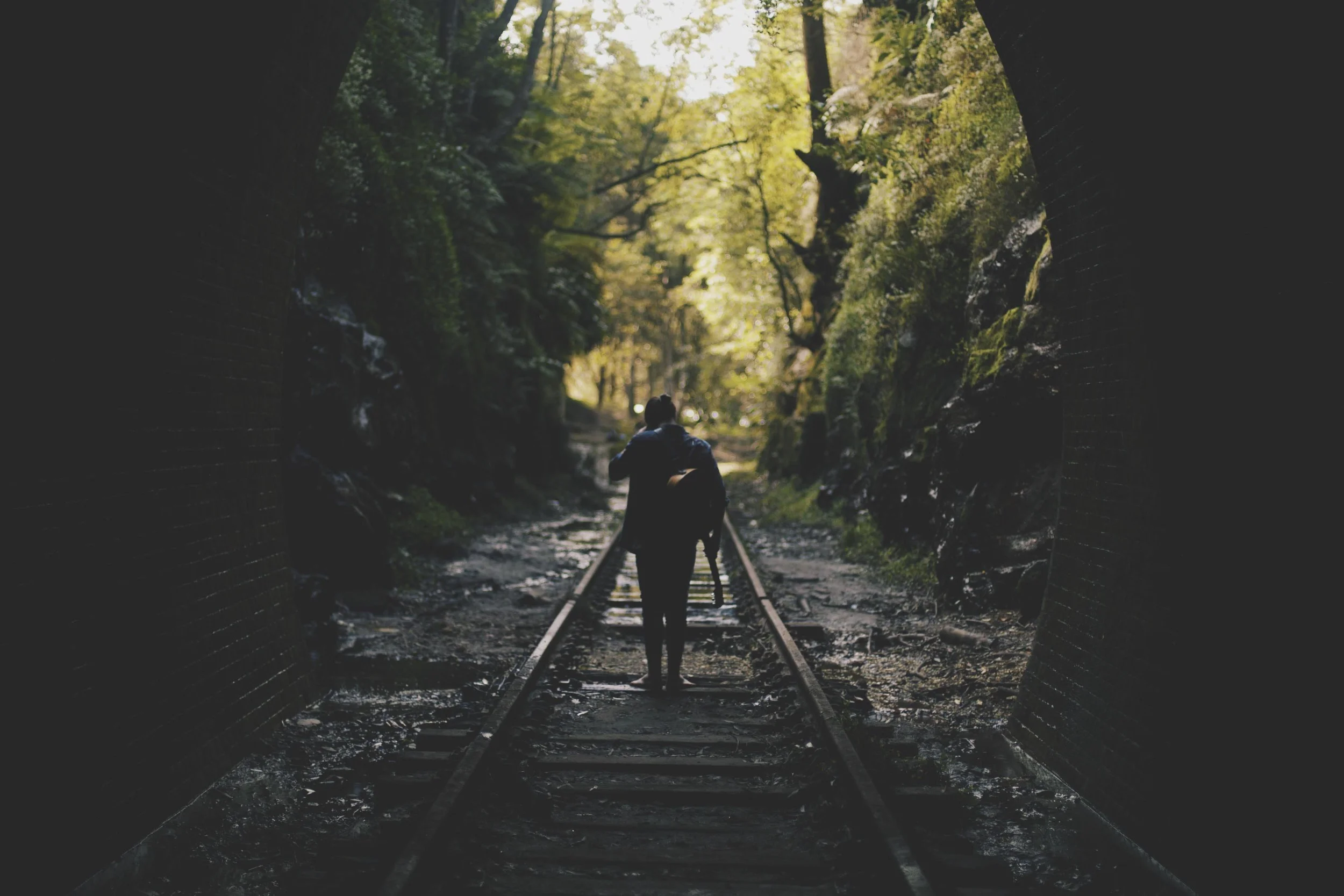 man standing in rainforest with guitar