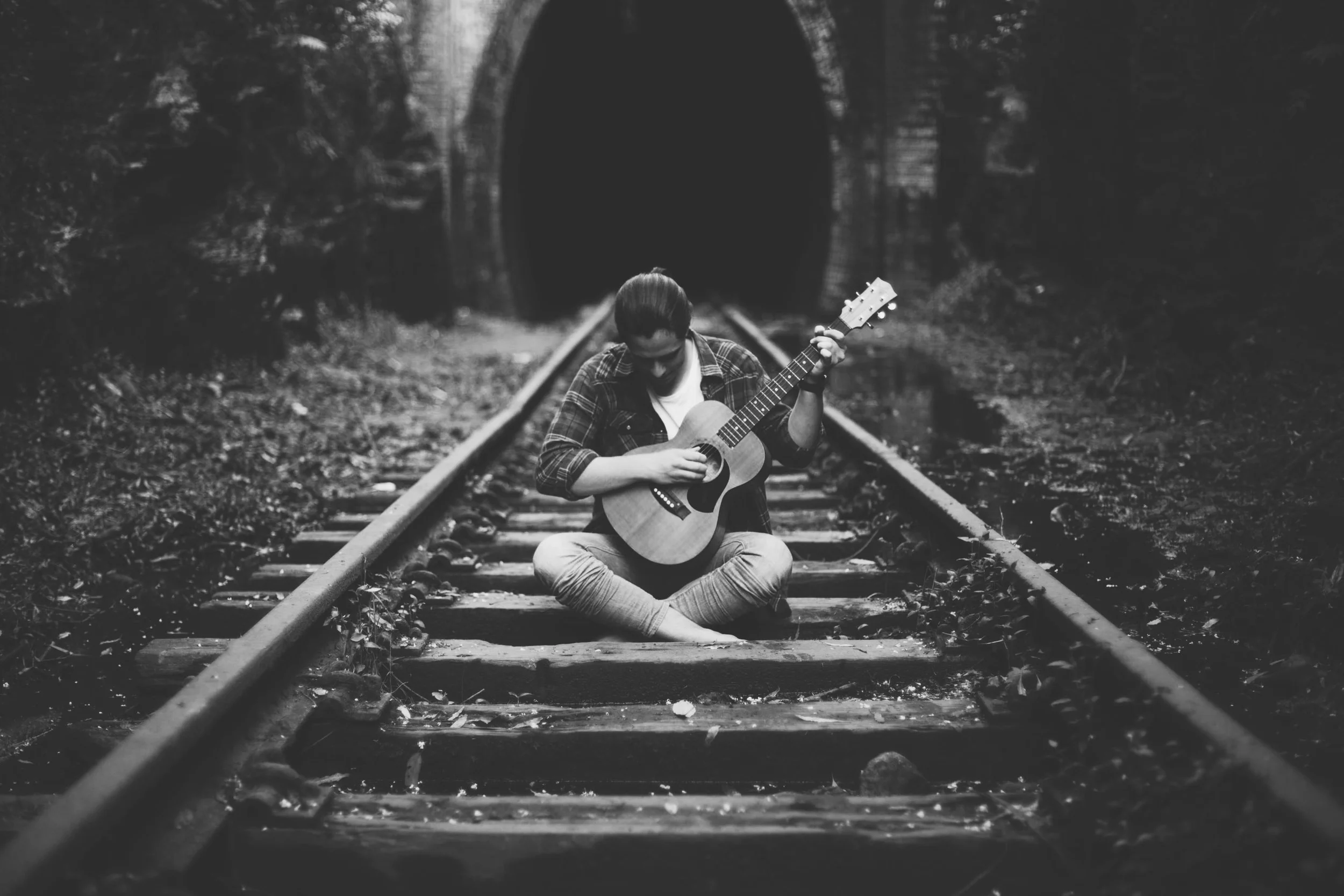 man standing in rainforest with guitar