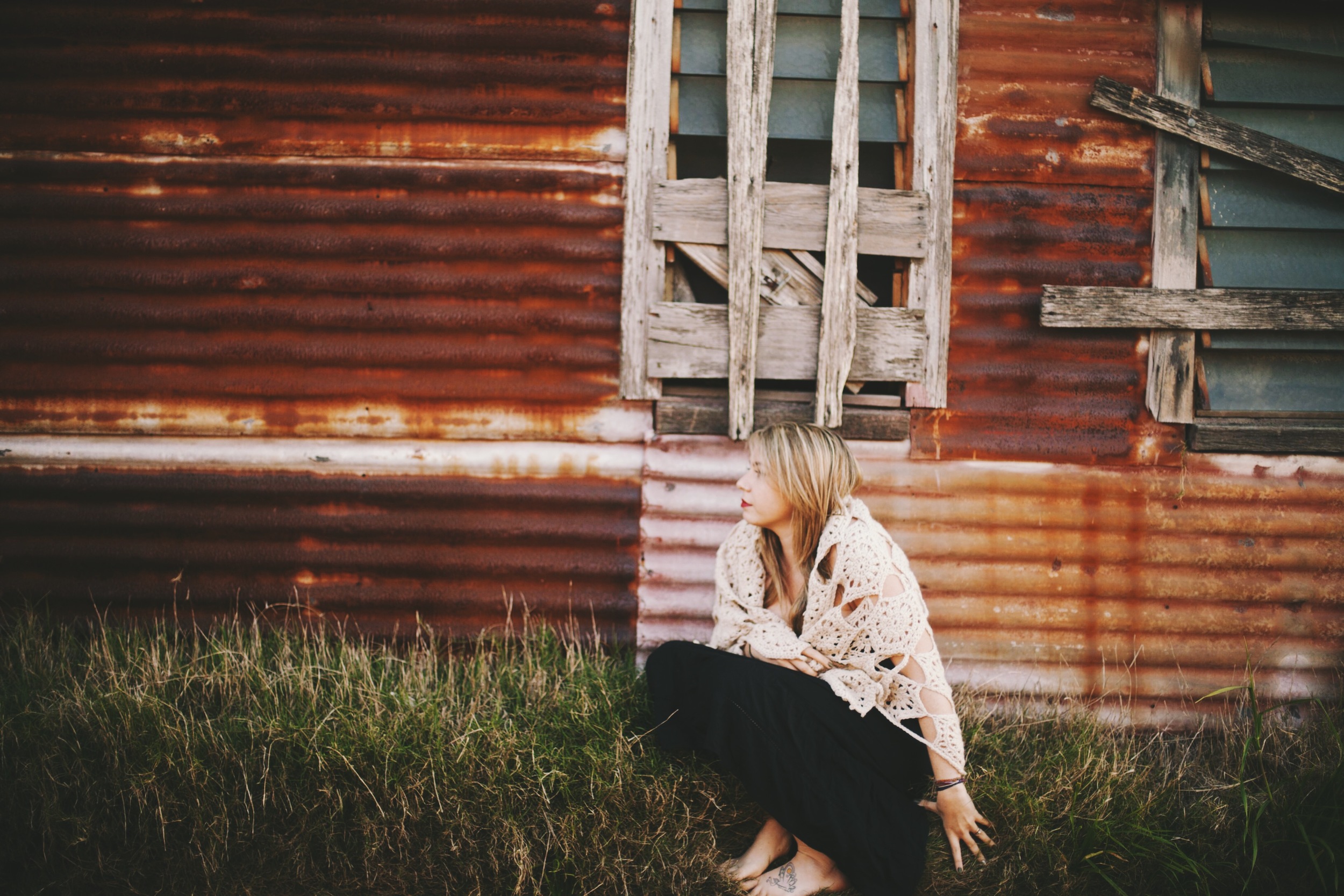 woman sitting near rustic cottage with golden light