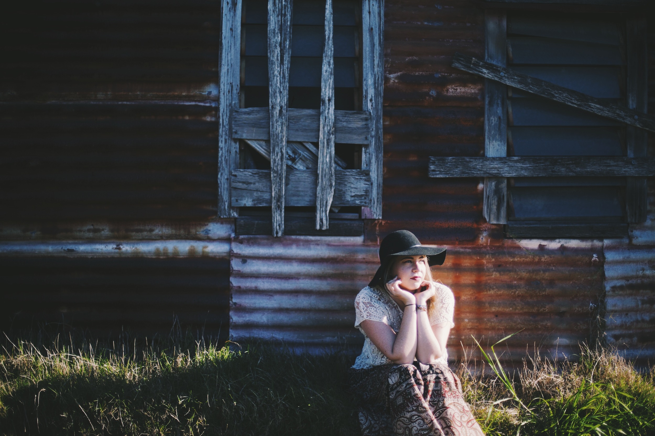 woman sitting near rustic cottage with golden light