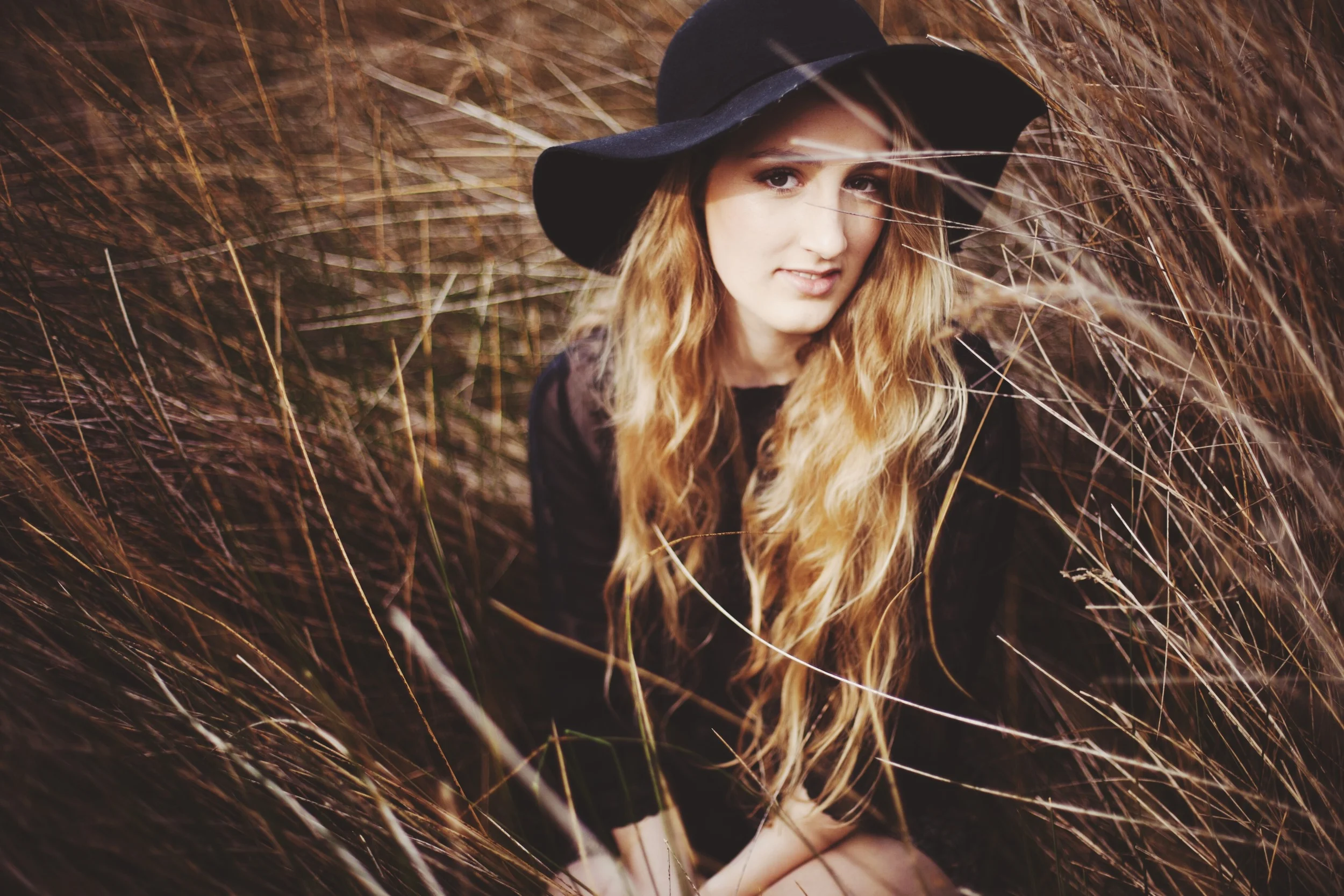 girl sitting in a field of wheat with guitar