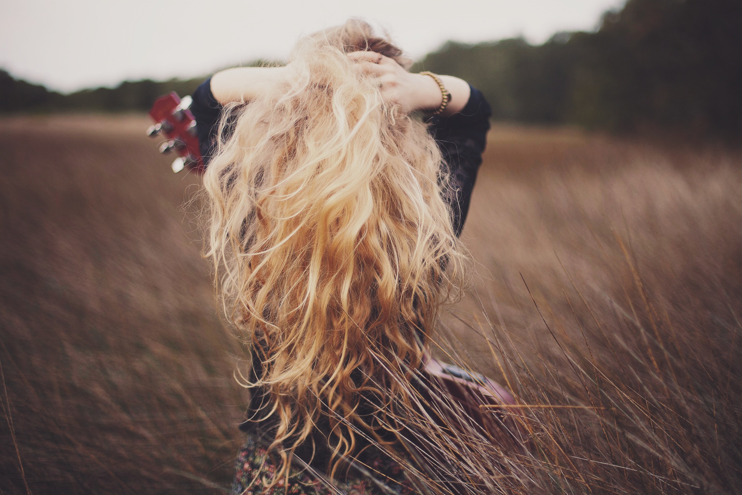 girl sitting in a field of wheat with guitar