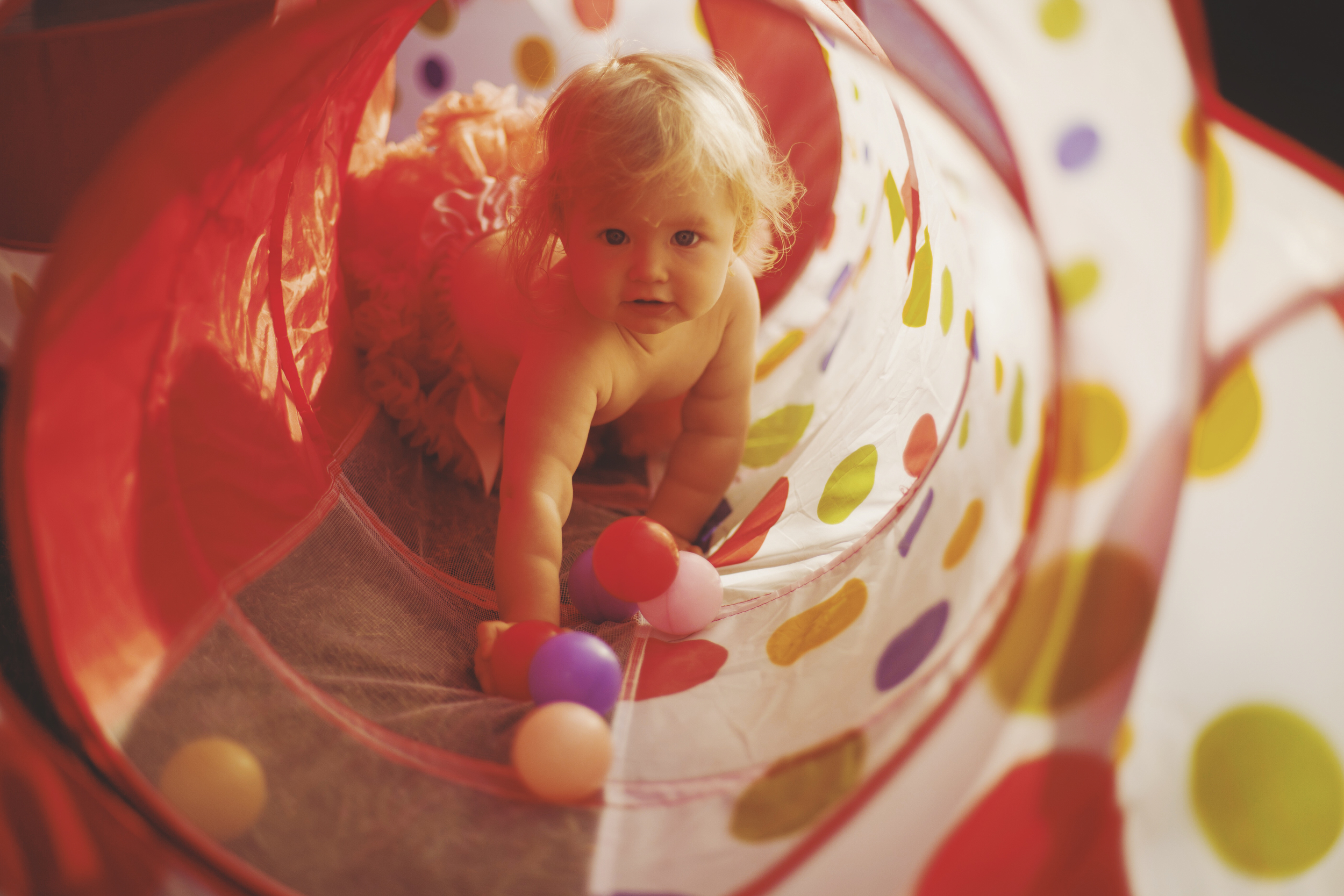 Baby crawling through colourful tunnel