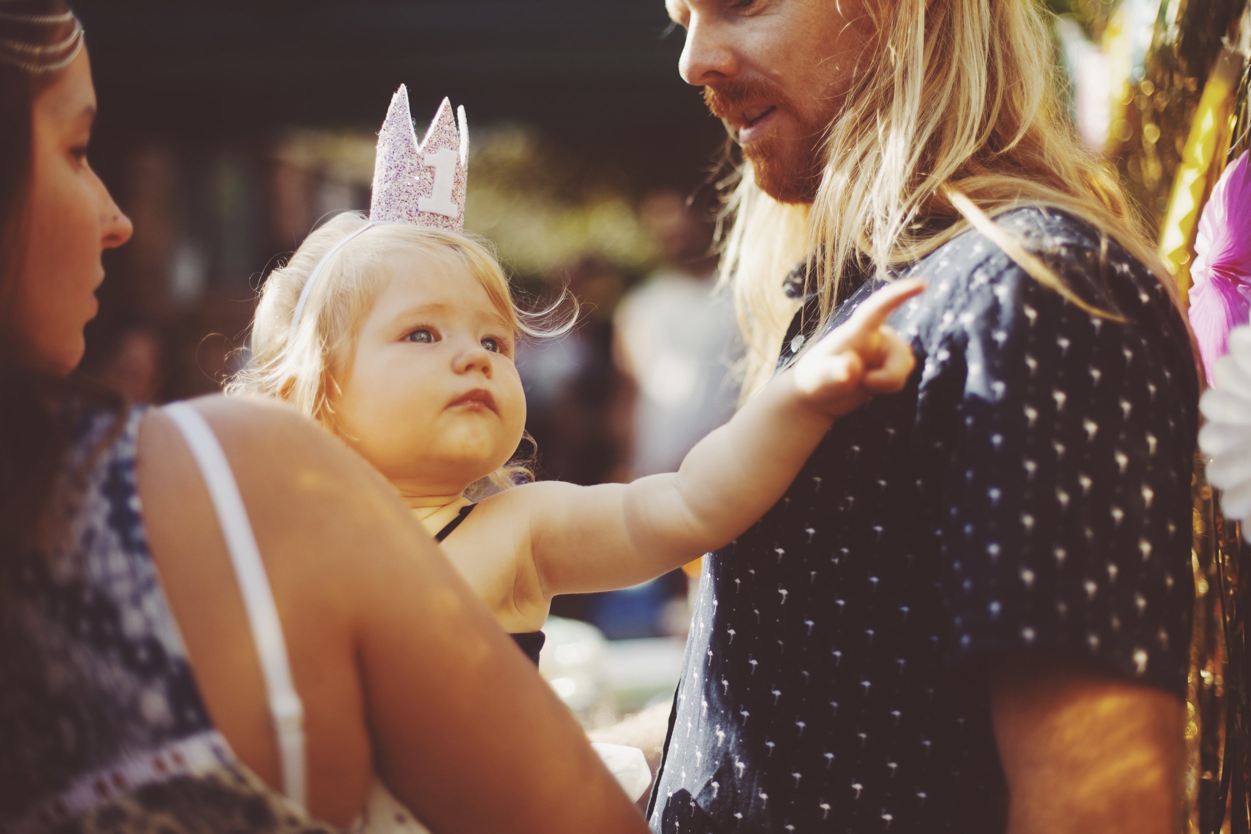 baby reaching for dad at first birthday party