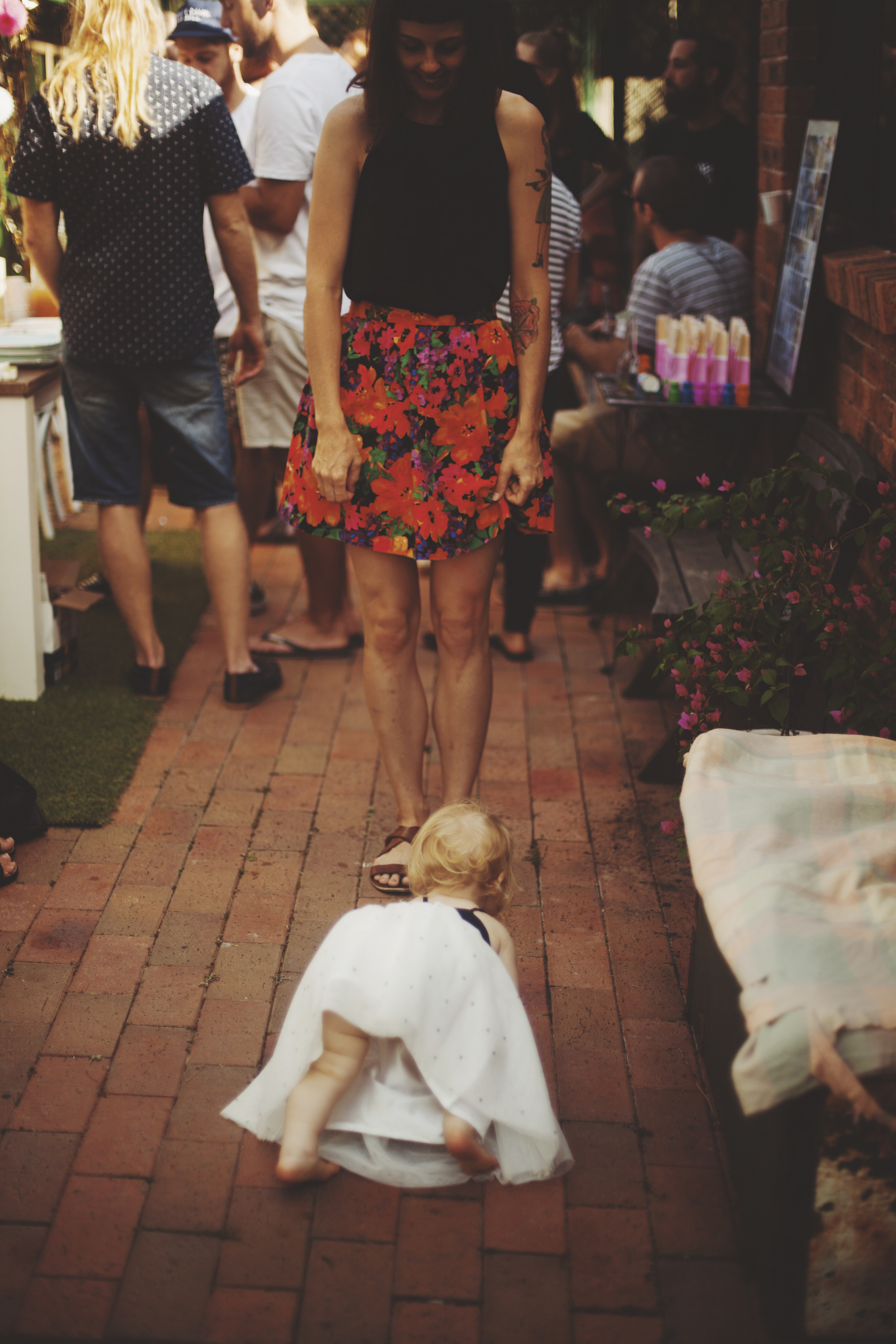 baby crawling on floor surrounded by people at first birthday party