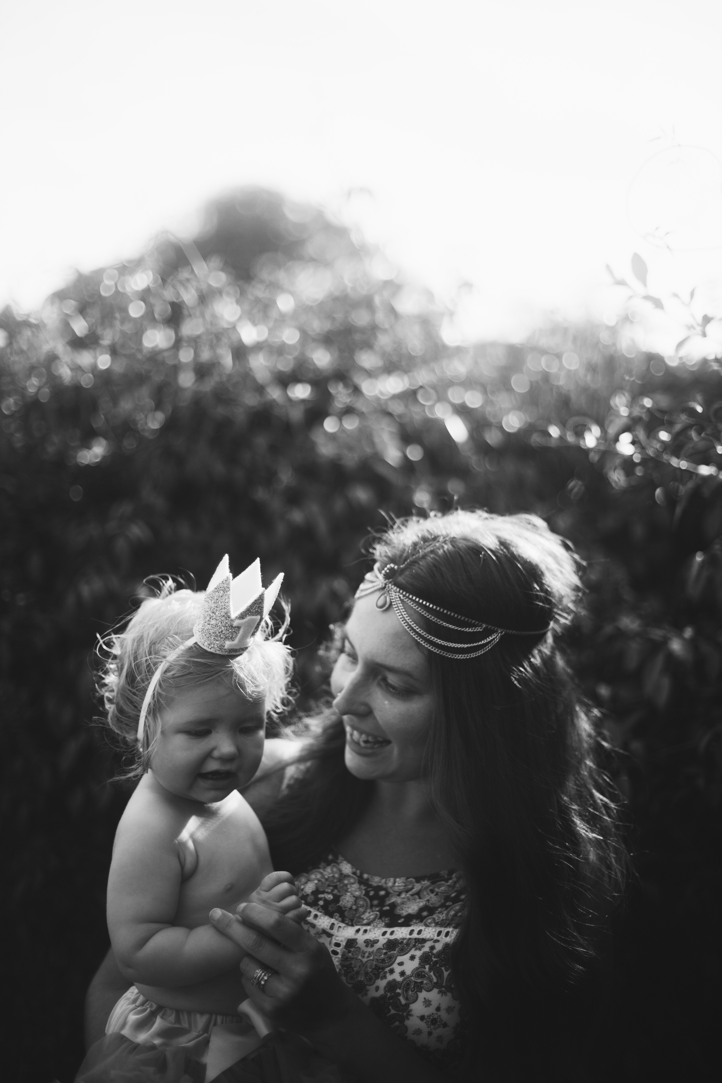 Baby wears birthday hat with mother at first birthday party