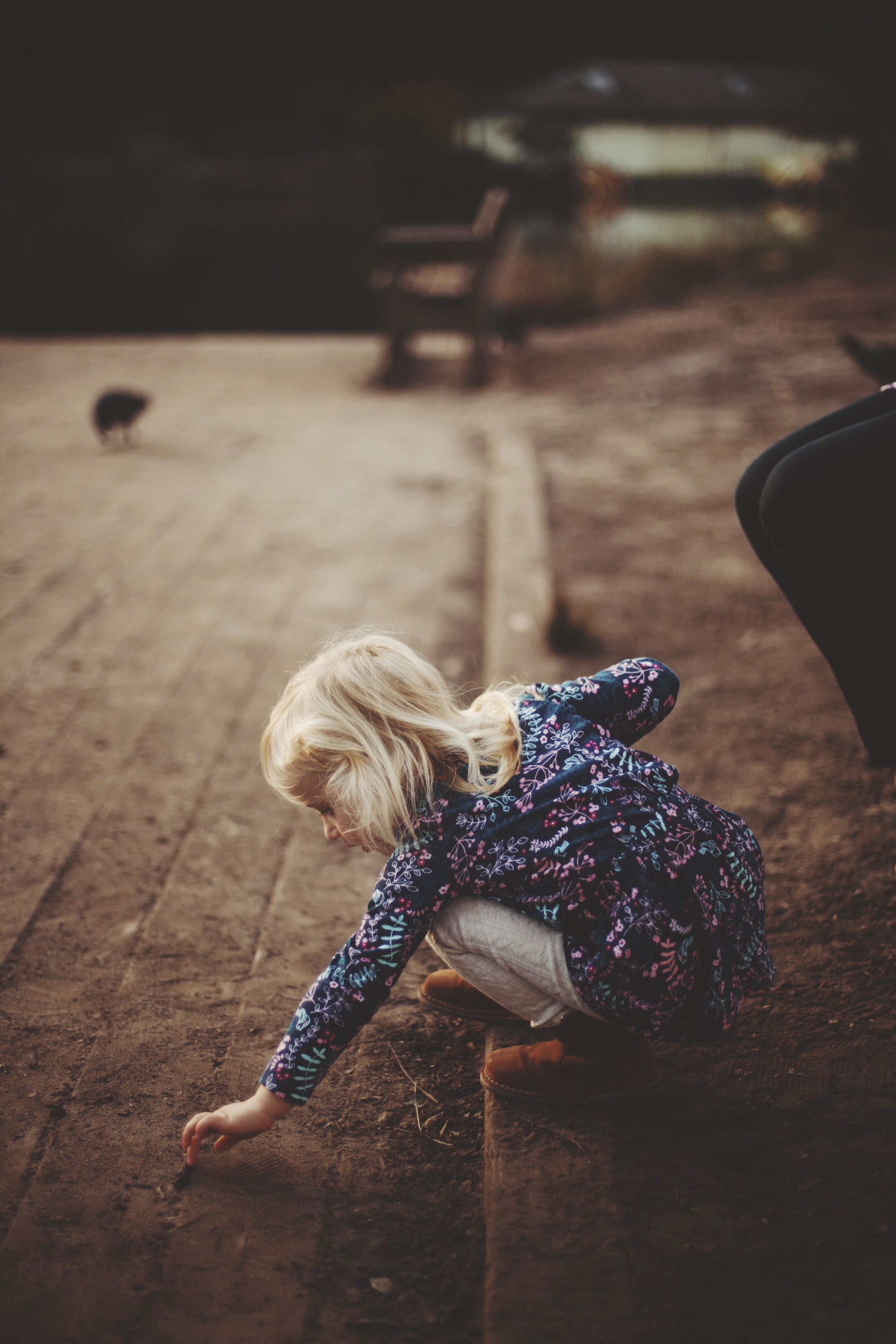 young girl bending to pick up something from the ground