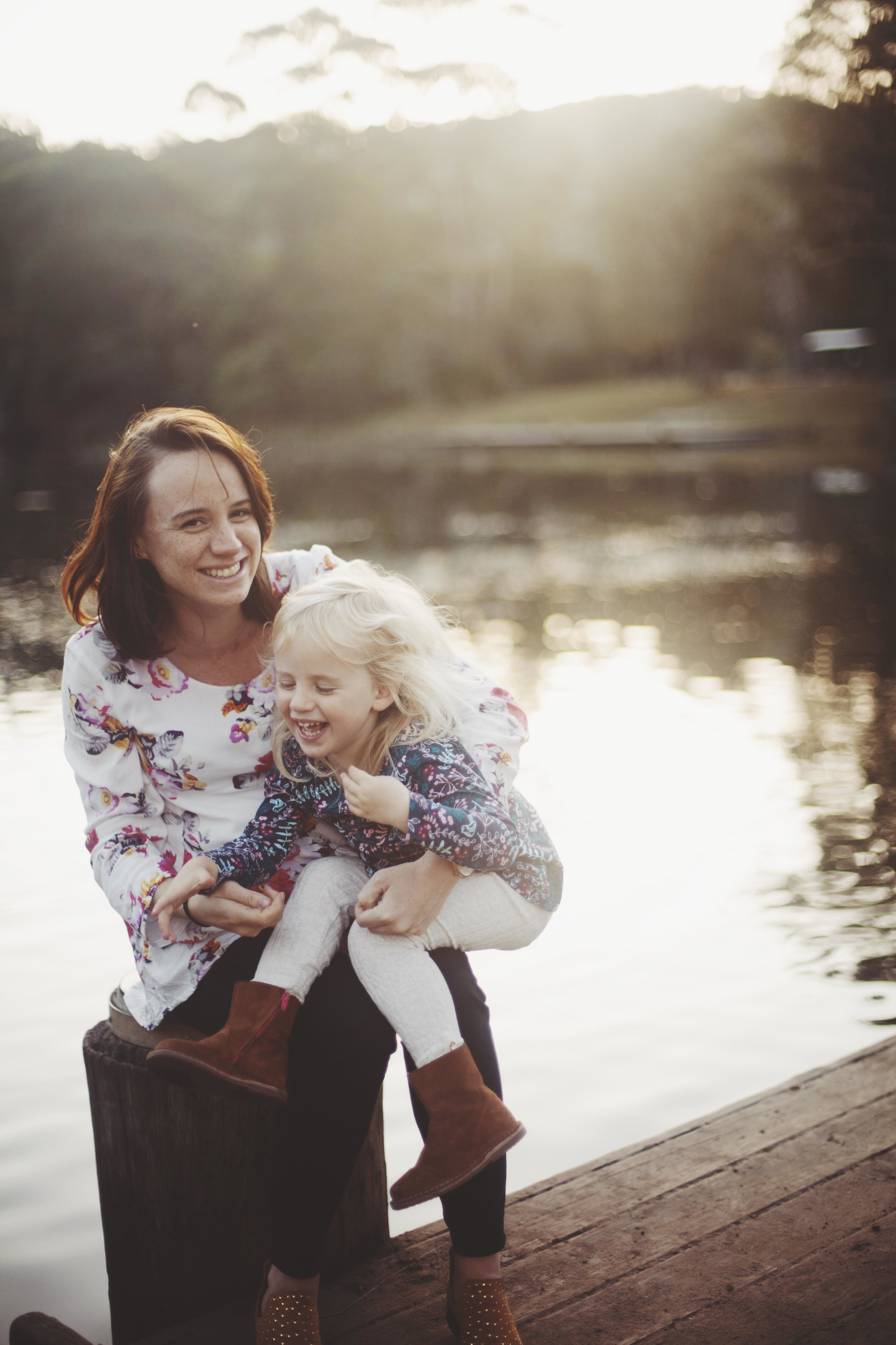 mother and daughter laughing together by the water 