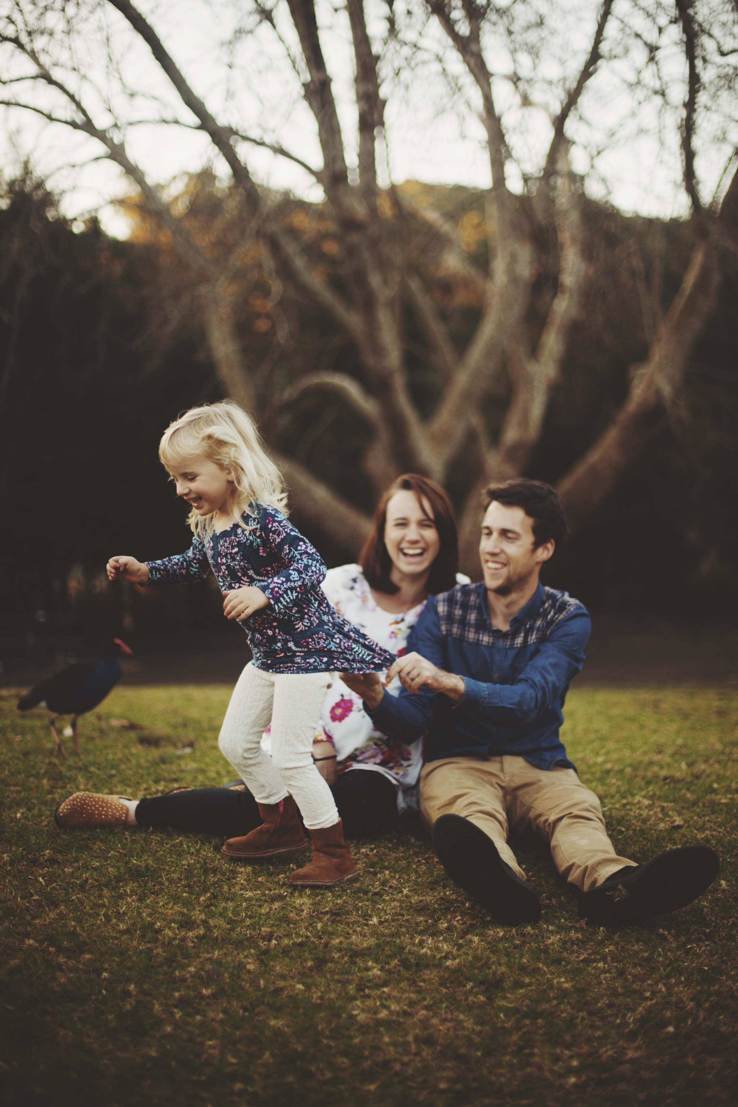 family sitting on grass daughter trying to run away