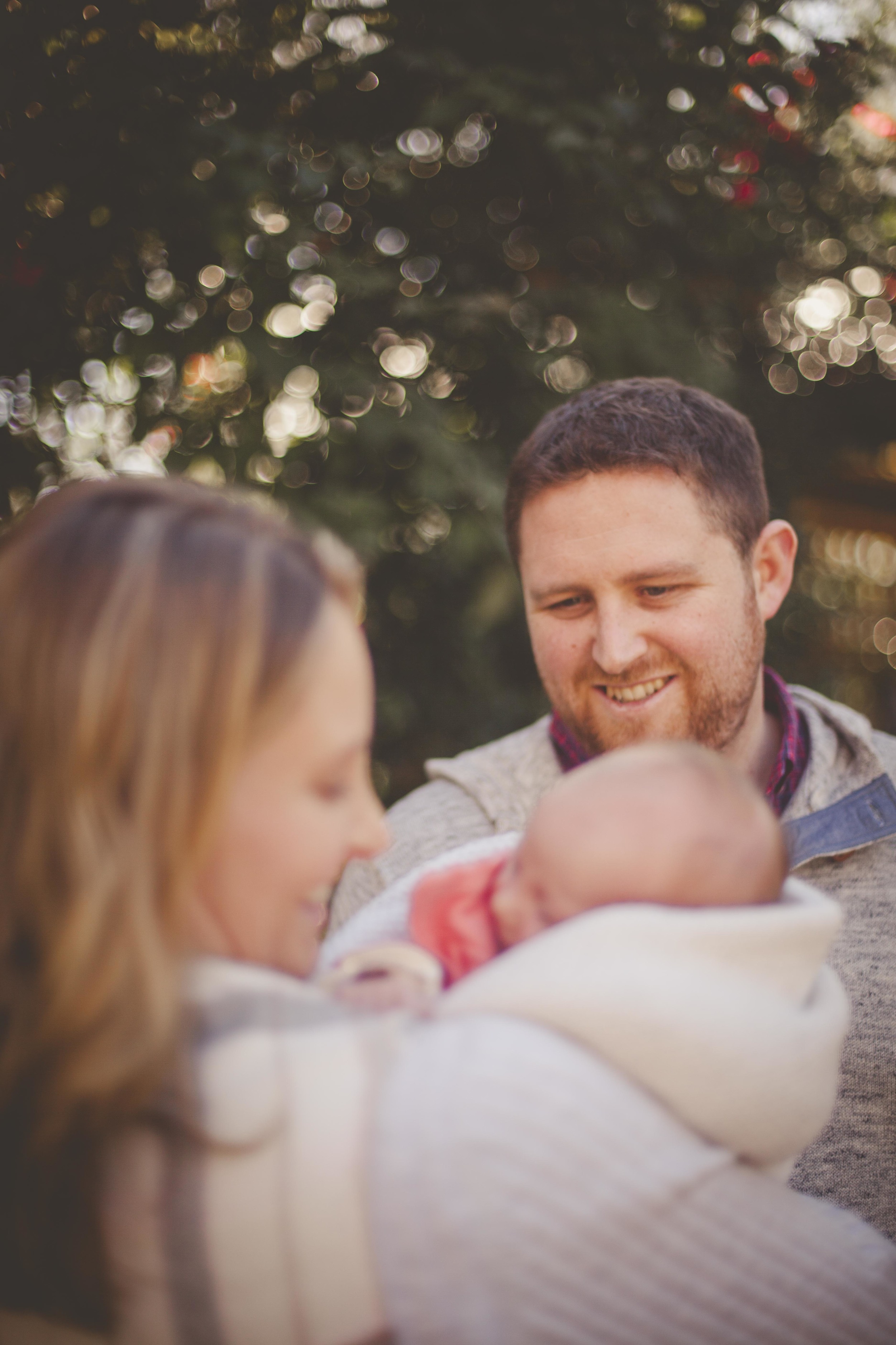 mother holding newborn father watching